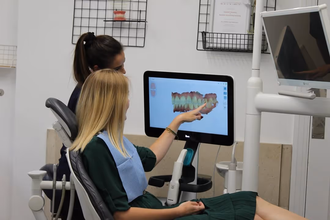 Dentist and patient looking at a dental 3D teeth scan on a screen in a dental clinic.