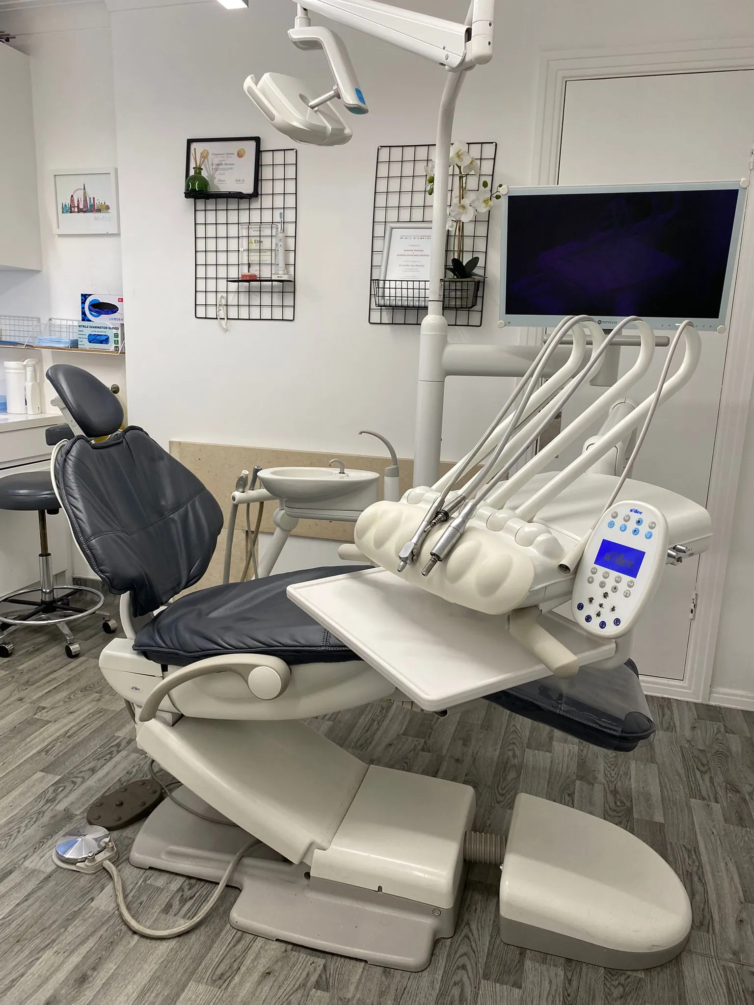 Dental office with a modern dental chair, attached dental instruments, a monitor, and clean white walls.