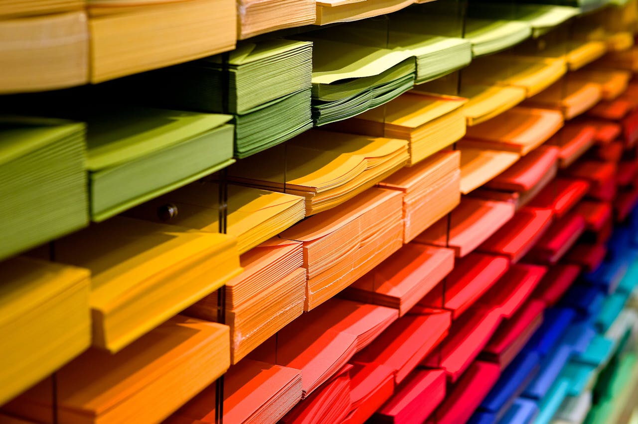 Shelves filled with neatly stacked paper sheets in a gradient of colors from green to blue.