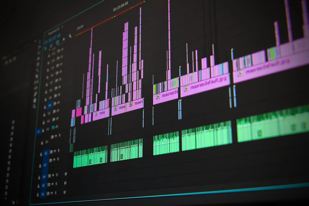 Close-up of a video editing timeline with multiple pink and green audio and video tracks on a dark interface.