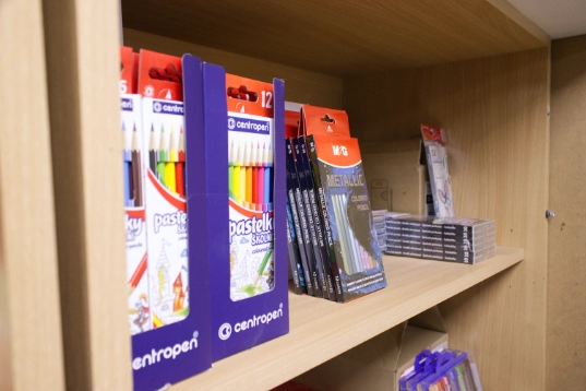Wooden shelf displaying packets of colored pencils and pencil leads.