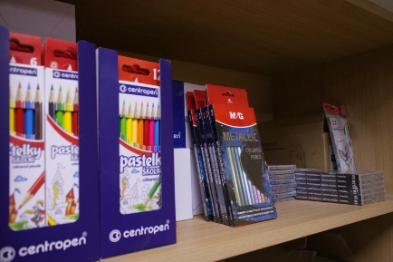 Shelf displaying boxed sets of colored pencils and packs of metallic-colored pencils arranged side by side.