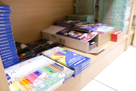 Store shelf displaying various colorful art supplies including colored pencils, crayons, and markers in boxes.