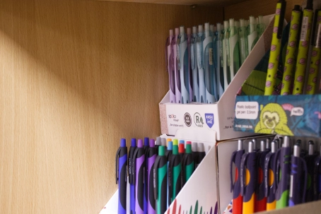 Display of colorful pens organized standing upright in white cardboard holders against a wooden background.