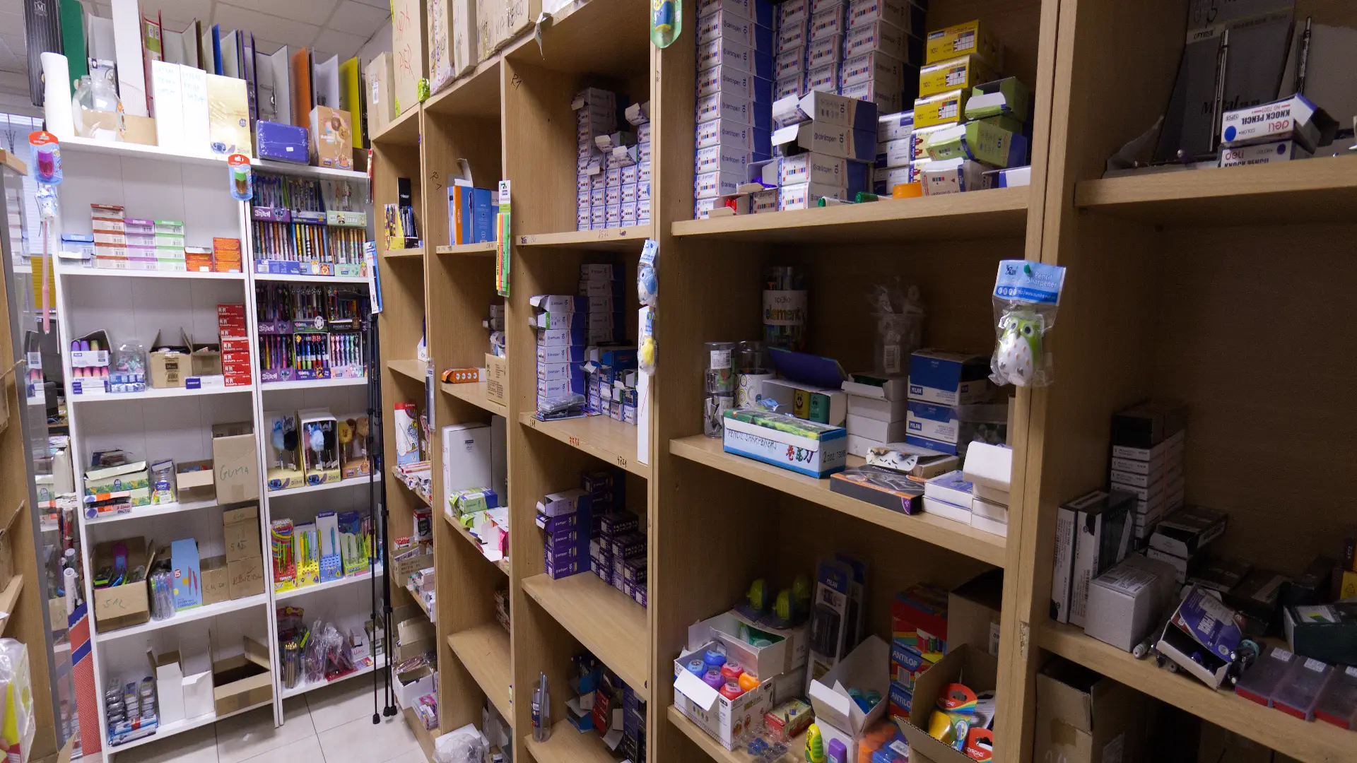 Storage room with wooden shelves filled with boxes and various stationery supplies.