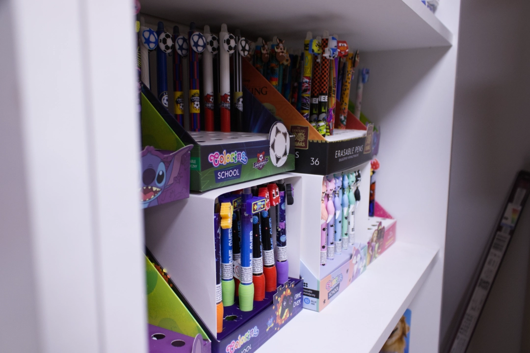 Stack of various notebooks and a clipboard with blank paper and a pen on a white desk next to a potted green plant.
