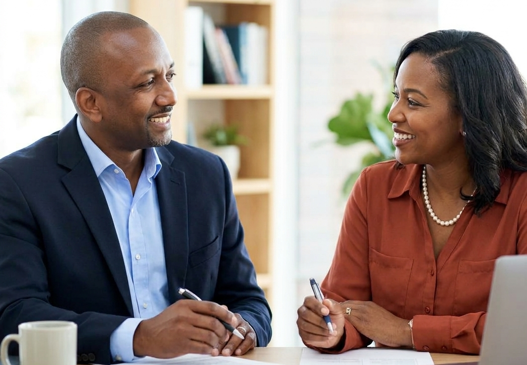 Dale and a client engaged in a discussion while looking at a laptop in a cozy café setting.