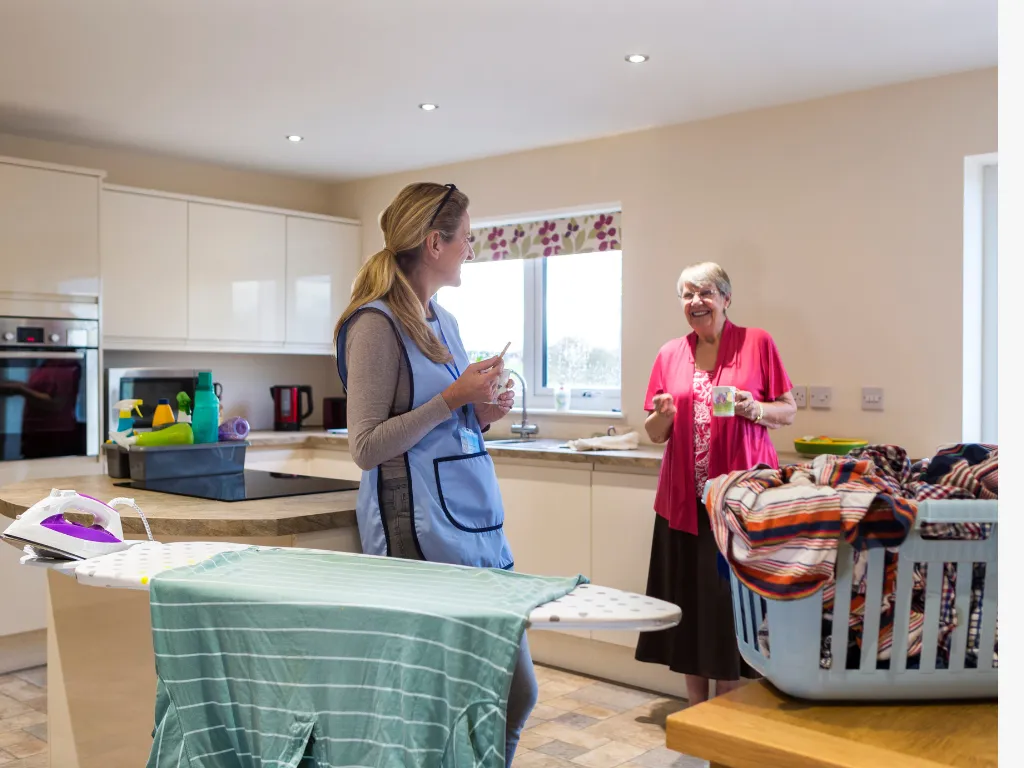 A caregiver helping an elderly women sort through her laundry.