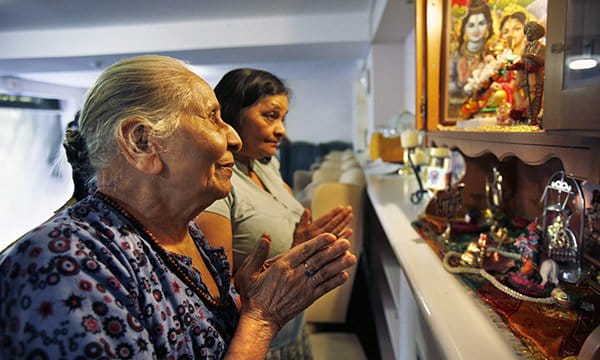 Caregiver assisting a senior women practice her faith.
