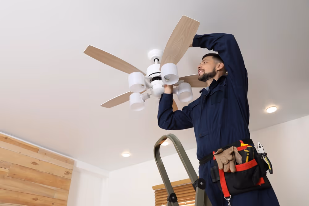 Technician installing modern ceiling fan lights.