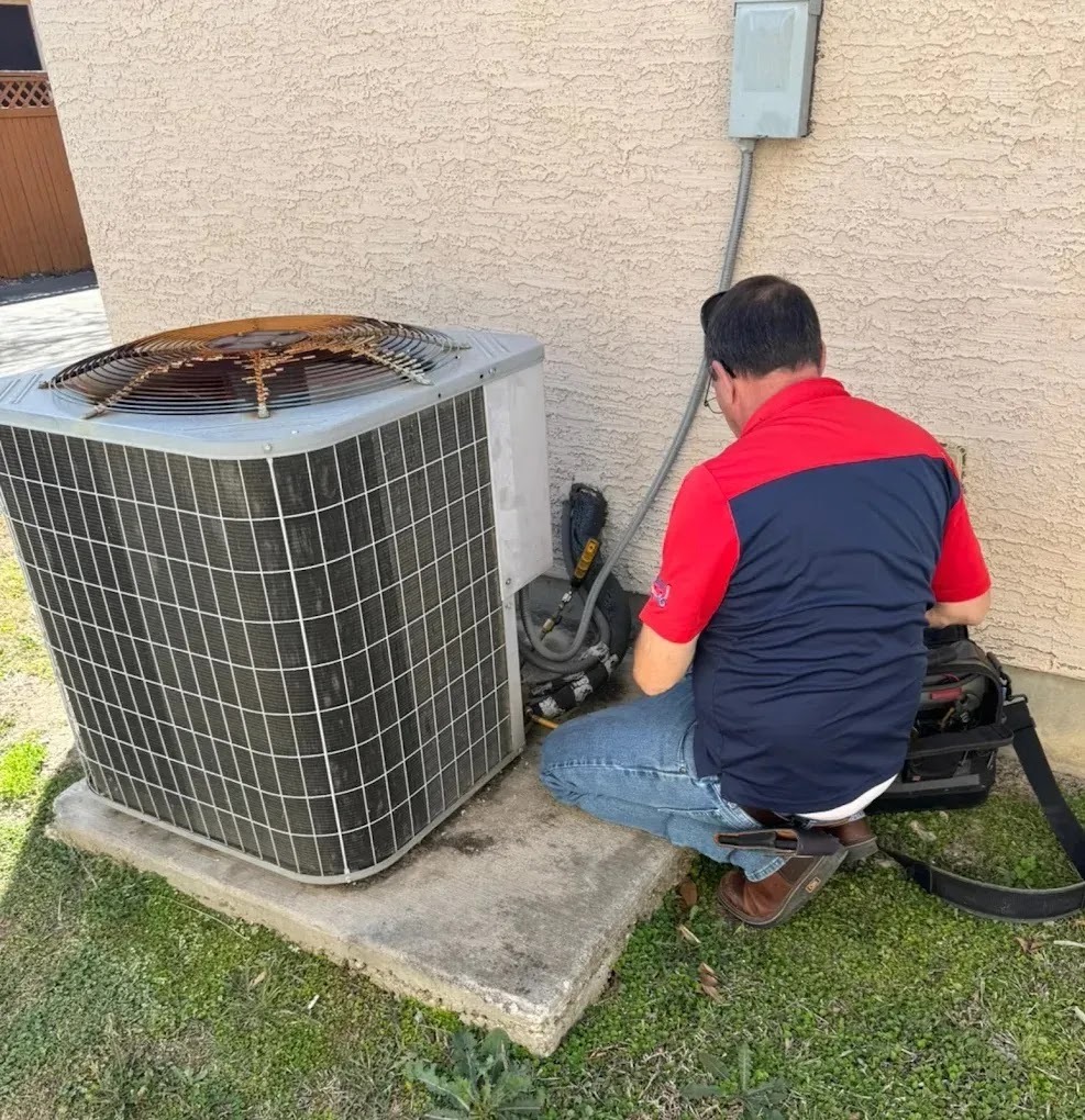 Technician performing seasonal AC maintenance in a sunny San Antonio backyard