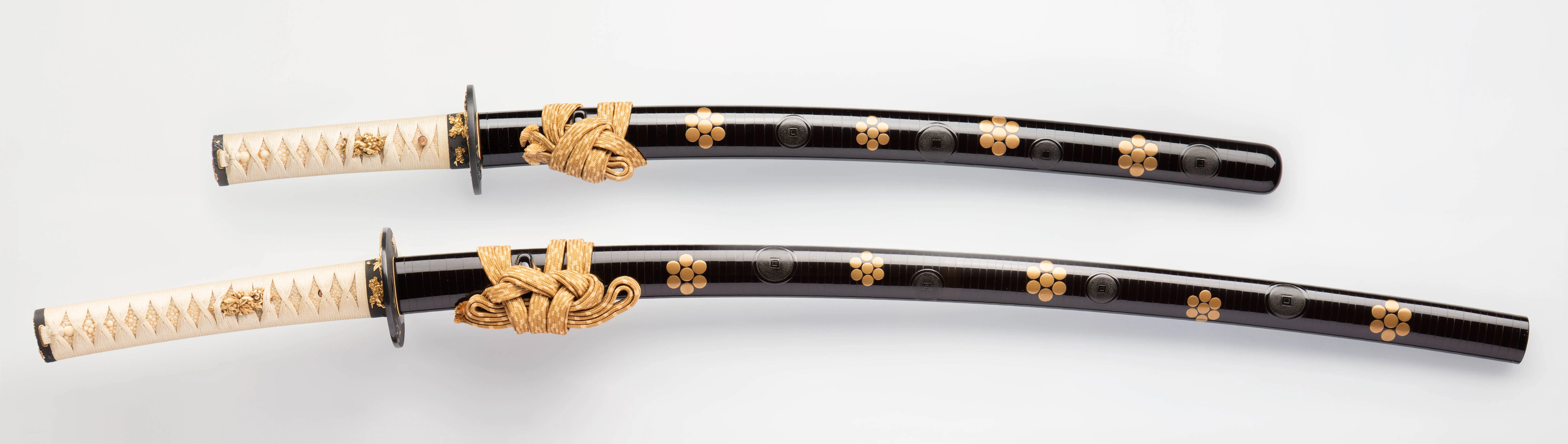 Deux sabres japonais katana à fourreaux laqués noirs ornés de fleurs dorées, armes antiques de collection