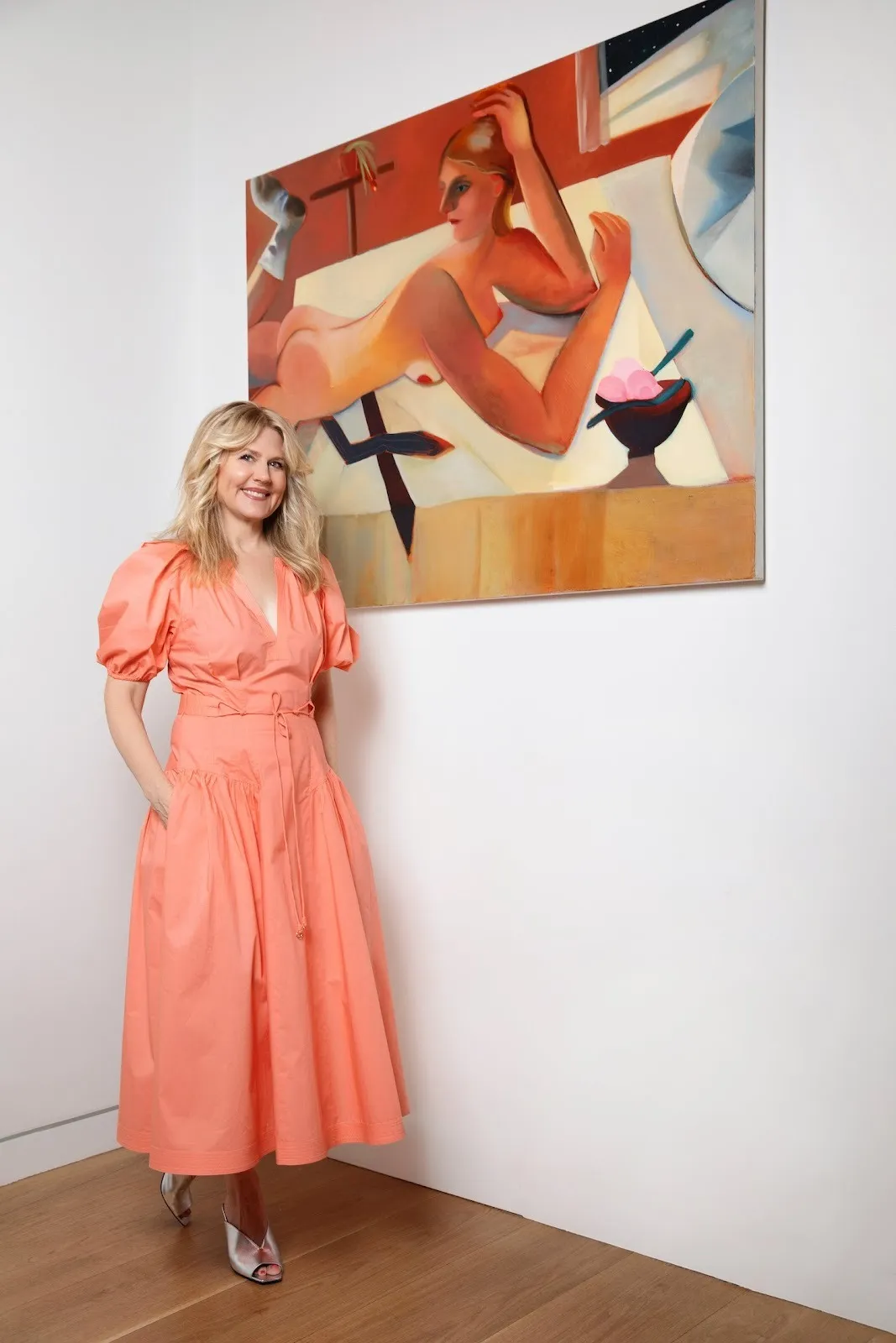 Jeanne Masel in coral dress in front of Danielle Orchard's Headlights, figurative painting of woman.