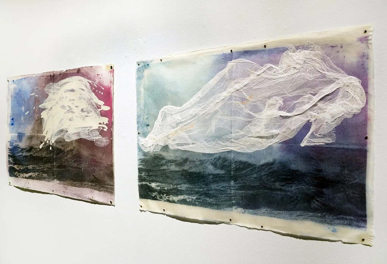 Blue, purple, brown, and red artworks False Dawn on gallery wall with ocean motif, collaged with cheesecloth depicting turbulent ocean with immigrant boats, Nazanin Noroozi.
