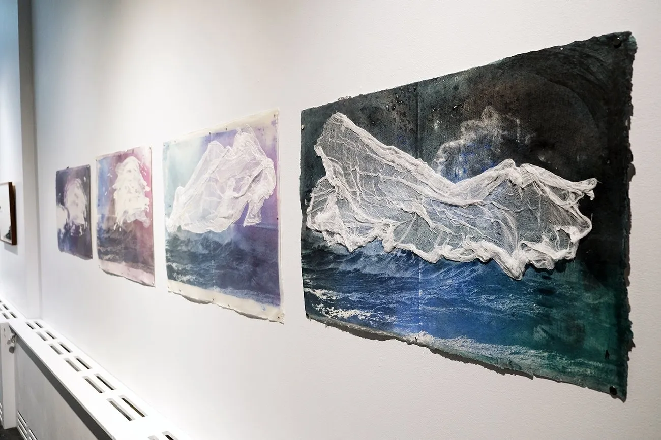 Four works on gallery wall with ocean motif, collaged with cheesecloth depicting turbulent ocean with immigrant boats, Nazanin Noroozi.