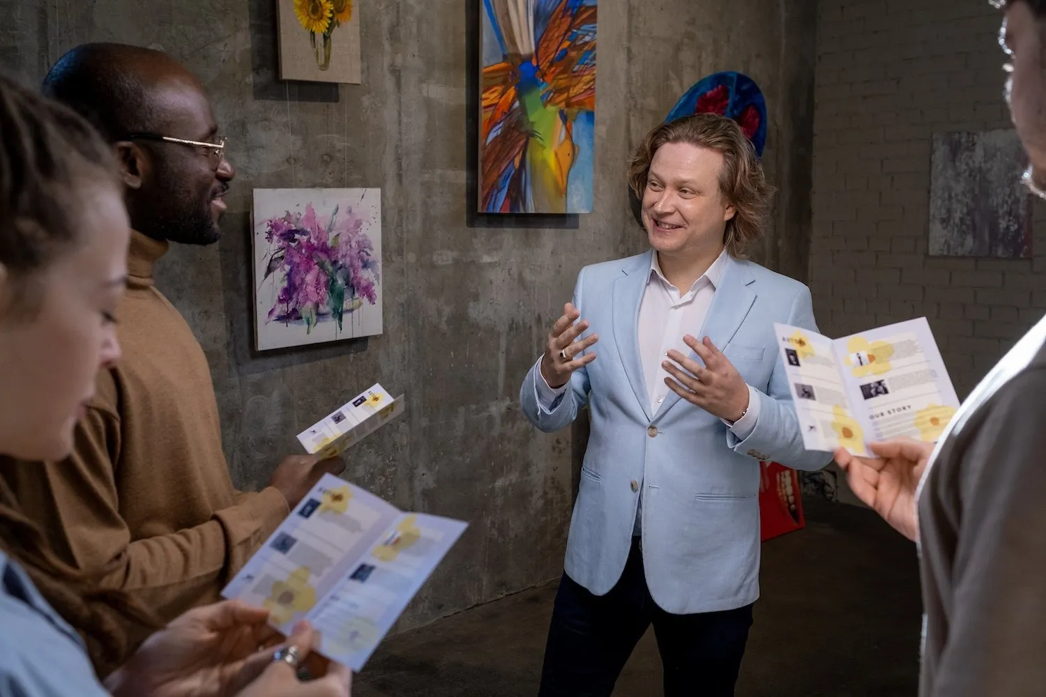 Happy artist interacting with guests of exhibition of his artworks.