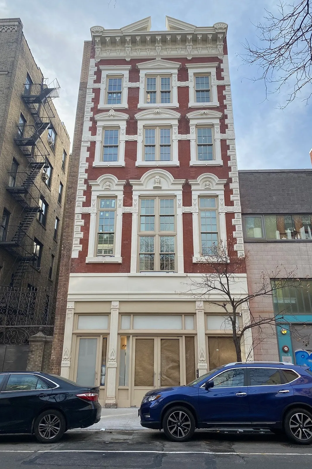 Red brick building with white window seals, exterior view of the renovated 74 East 4th Street La MaMa theater venue.