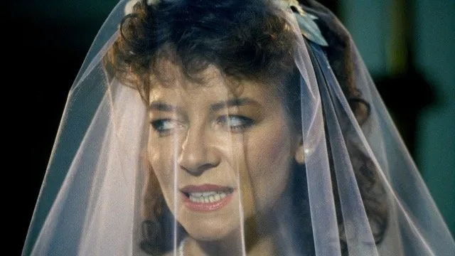 Girl wearing wedding veil and pearl earrings and necklace, with expression of resentment, head half turned, for those still from Hellraiser by Clive Barker, Arrow films.