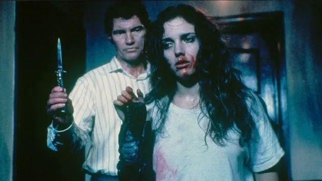 Caucasian men in striped collared shirts standing with knife behind long-haired girl with blood all over her mouth in a dark room, photos still from Hellraiser by Clive Barker.