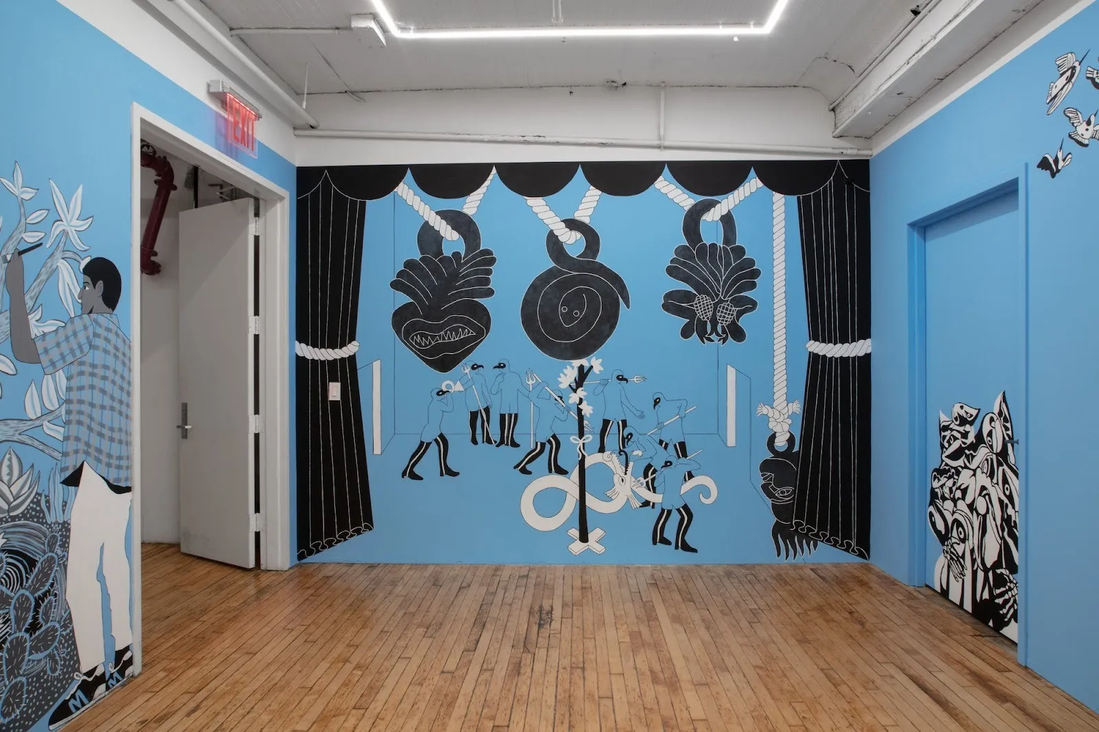 Installation view of site-specific mural for Tell Me How It Ends by Miguel Martinez, Gallery room with blue walls and black and white Mexican traditional imagery, GRIMM.