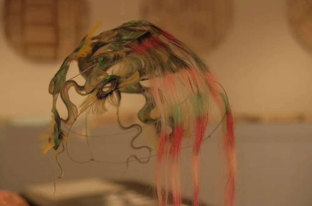 Colorful wavy wig mounted on welded iron shelf on view ig by Tomihiro Kon in Current Plans’s booth at The Salon by Nada and The Community.