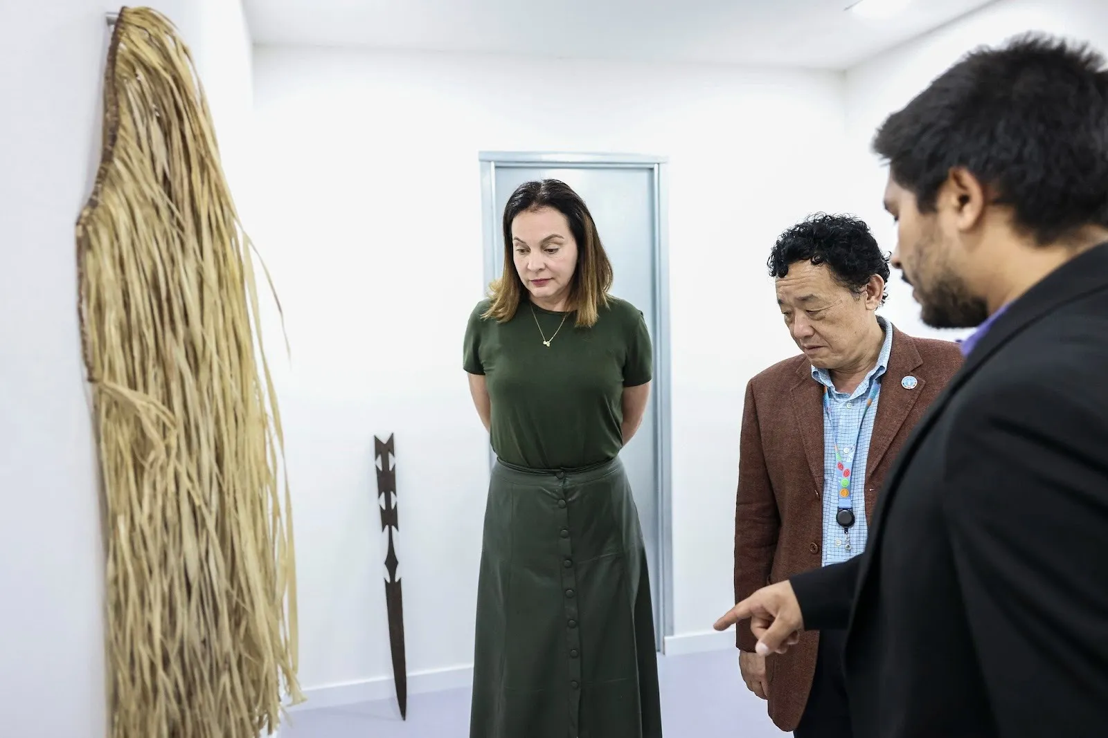 From the left, Carla Barroso Carneiro, Brazil ambassador and permanent representative to FAO, QU Dongyu, FAO director-general, and Lucas Memmola, artist, pointing to Shanenawá artifacts, visiting the antechamber of Paradise Bank, Rome, 2024.