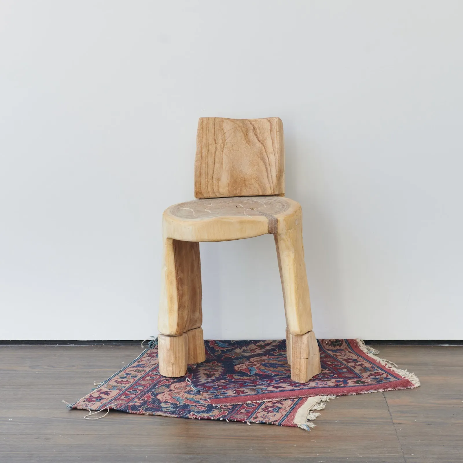 Wooden chair on persian rug as sculpture installation against white gallery wall, Christopher Al-Jumah, Untitled, 2024 persian silkwood 25 allen street gallery group exhibition new york now.