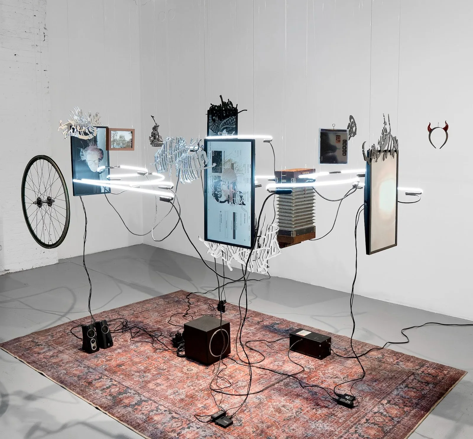 Digital avatars of artist shown on computer screen with wires connecting memento mori and neon lights, installation view of Frank WANG Yefeng, Avatopology at NARS Foundation, curated by Natasha Chuk.