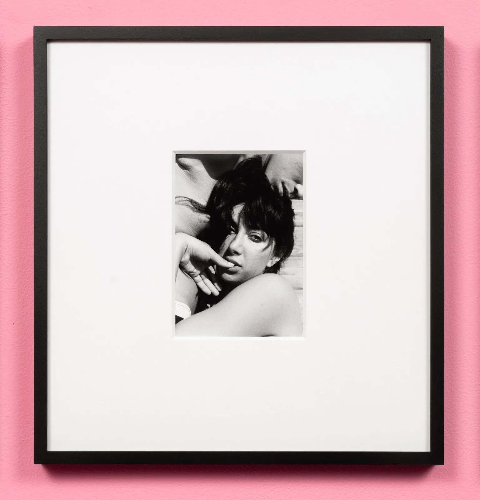 Chuy Medina, Martine and Dara (Fire Island), black and white portrait of a woman sucking her thumb naked, installed against pink wall, Camp and feminine subjectivity group exhibition bad girls at OCD Chinatown.
