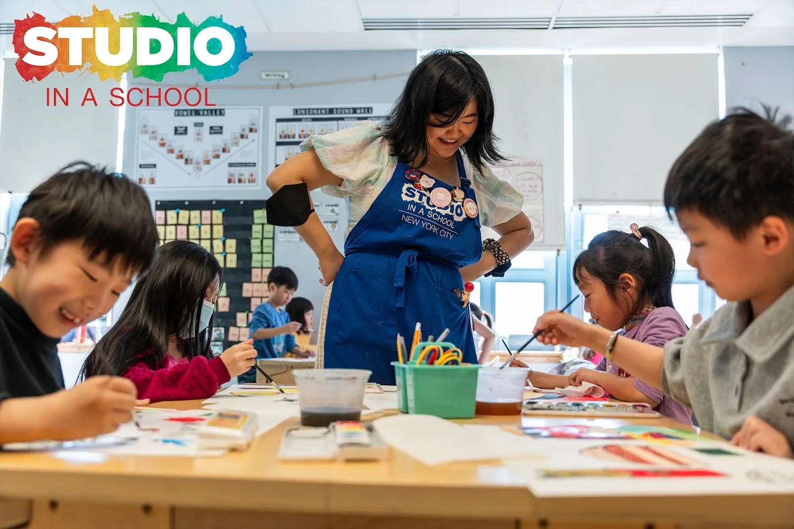 Art education nonprofit Studio in a School Artist Instructure Loraine Zhou working with 2nd grade students on an oil pastel and watercolor unit focused on stories of food, memories, and culture, at P.S. 244, Queens.