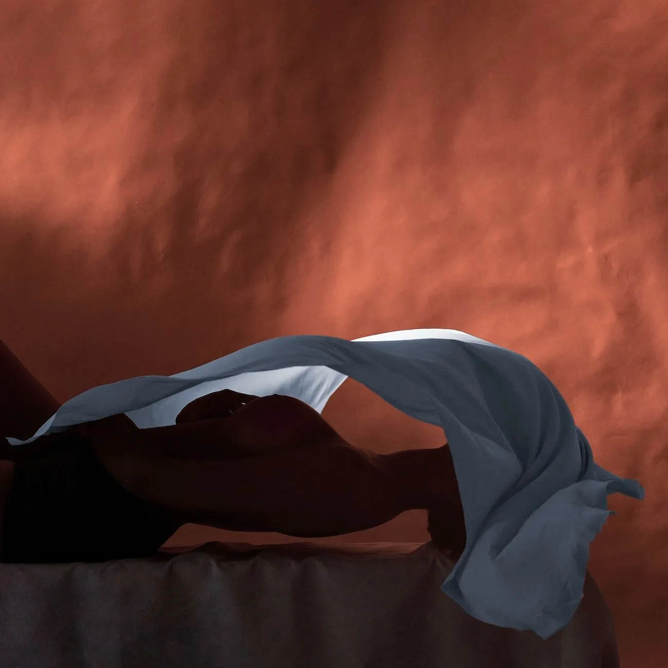Juan Sebastian, La Caricia, 2020 photograph of nude body underneath white Veil against red background by Columbia immigrant artist.