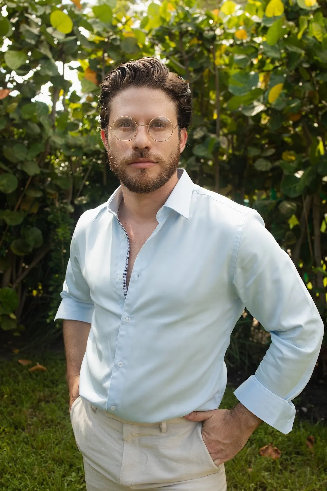 Portrait of men wearing Cerulean blue button down shirt and beige pants with hands in pocket in the garden, Colombian immigrant artist photographer Juan Sebastian.