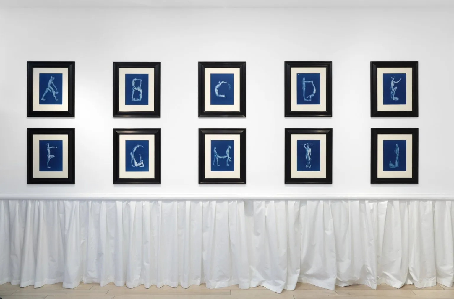 Installation view of Peter McGough solo exhibition Alphabet, cyanotype photographs of nude male ideal body posing in letters, karma gallery.