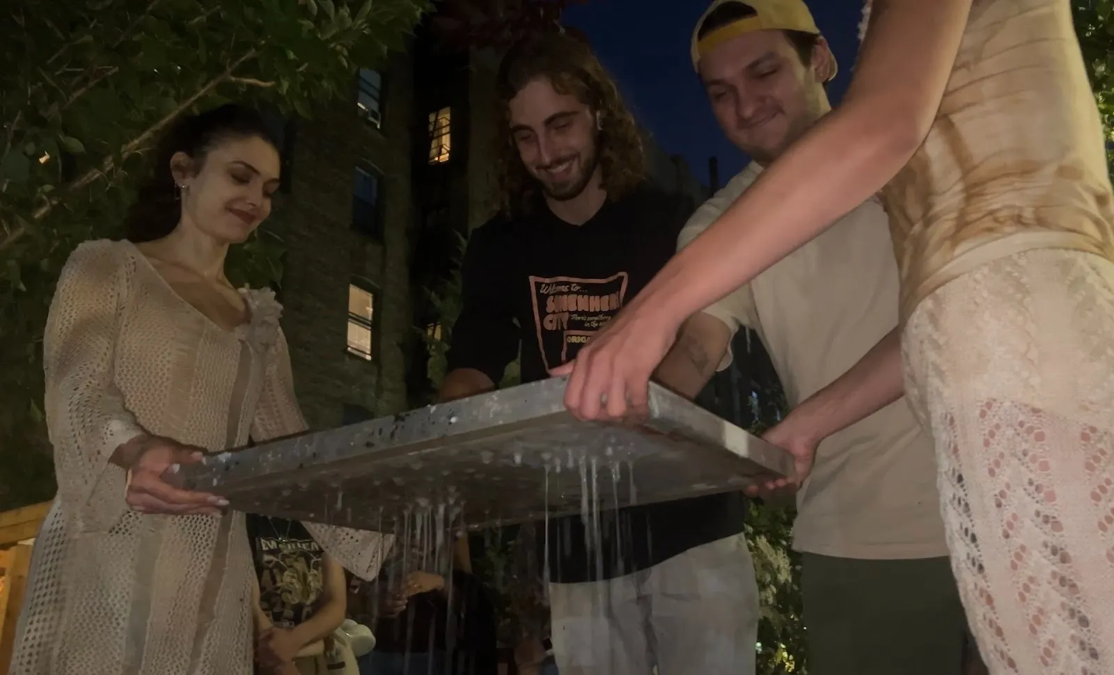 Two performers wearing white costume at garden of voices, frank white memorial garden help participants make pulp paper by draining liquid, project iii and embodied earth collaboration, interview with nicole jackson and kasey broekema.