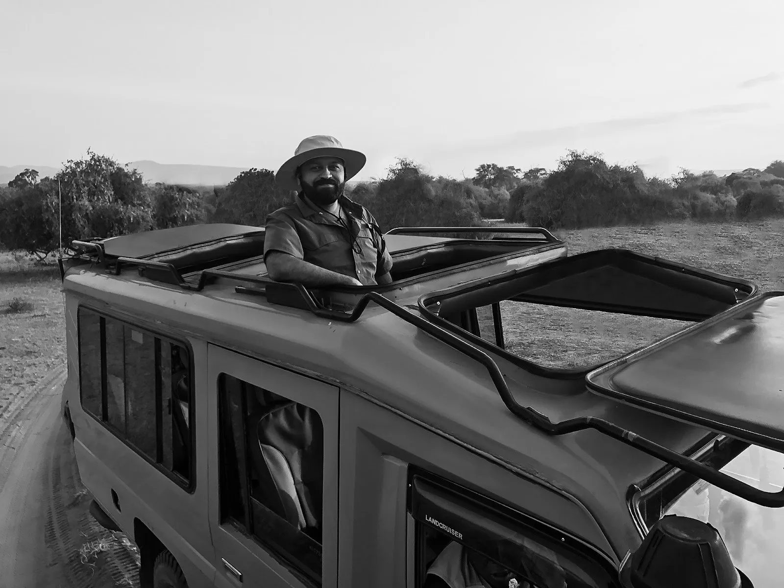 Black and white photograph of Indian American man in safari Land Cruiser, nature and wildlife photographer Mital Patel.