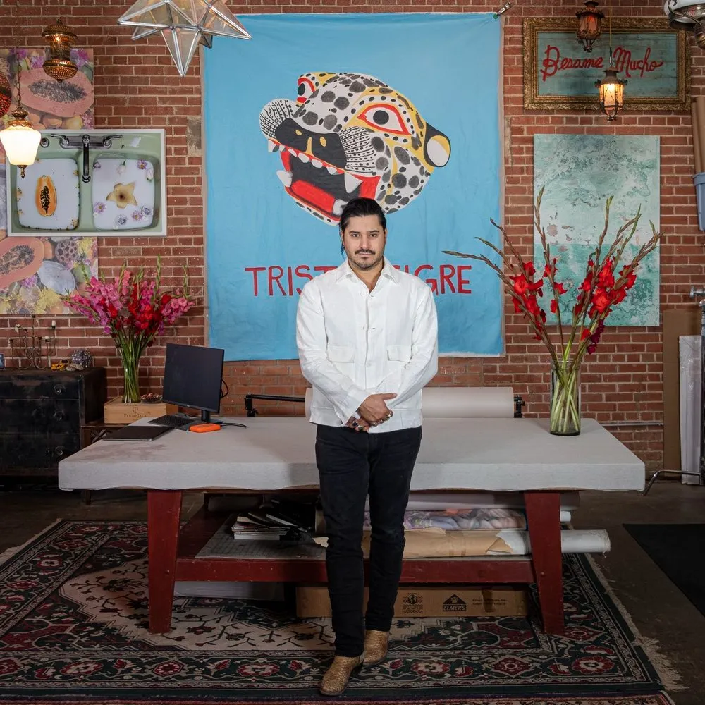 Jorge Villarreal, Latin man standing in front of colorfully decorated Interiors, photographer and founder of artist residency casa cache.
