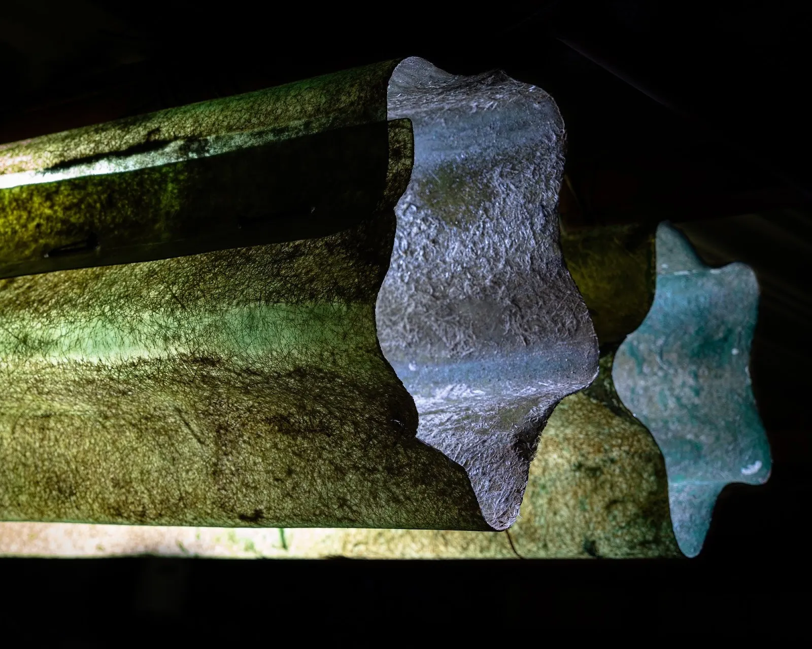 Bronzy green installation with flattened basketball, sculptural artwork by Filippo Vogliazzo, detail of Light Sleepers photographs by Jorge Villarreal, Casa Caché artist residency.