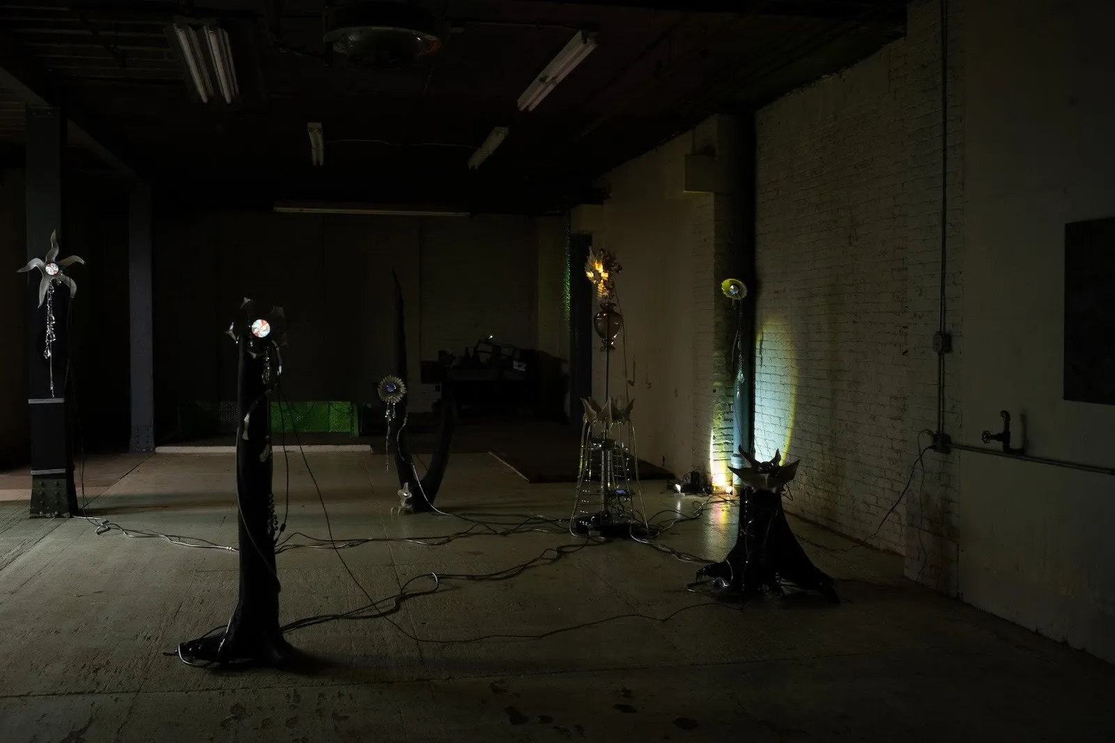 New Uncanny gallery, group exhibition comfort zone, installations in abandoned factory, vadim pugin and diane severin nguyen, curated by dasha Aksenova, towers of mythical metal faces connected by wires.