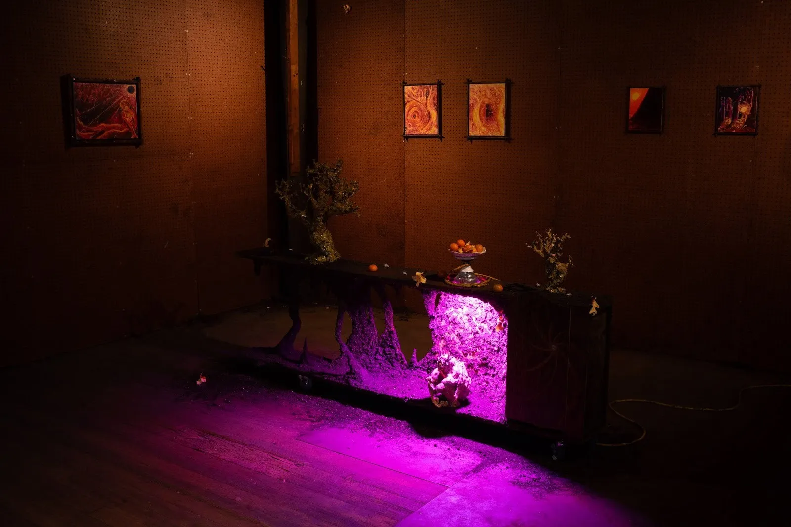 New Uncanny gallery, group exhibition comfort zone, installations in abandoned factory, amadeo morelos curated by dasha Aksenova, Stone table with pink neon lights and fake plants, paintings on Factory metal walls with orange peels and satyr.