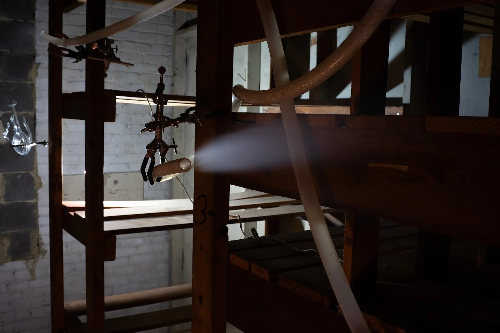 New Uncanny gallery, group exhibition comfort zone, installations in abandoned factory curated by dasha Aksenova, miriam simun, a wet chemical trace, silicone tubes over wood Shelf with flower scented vapor.