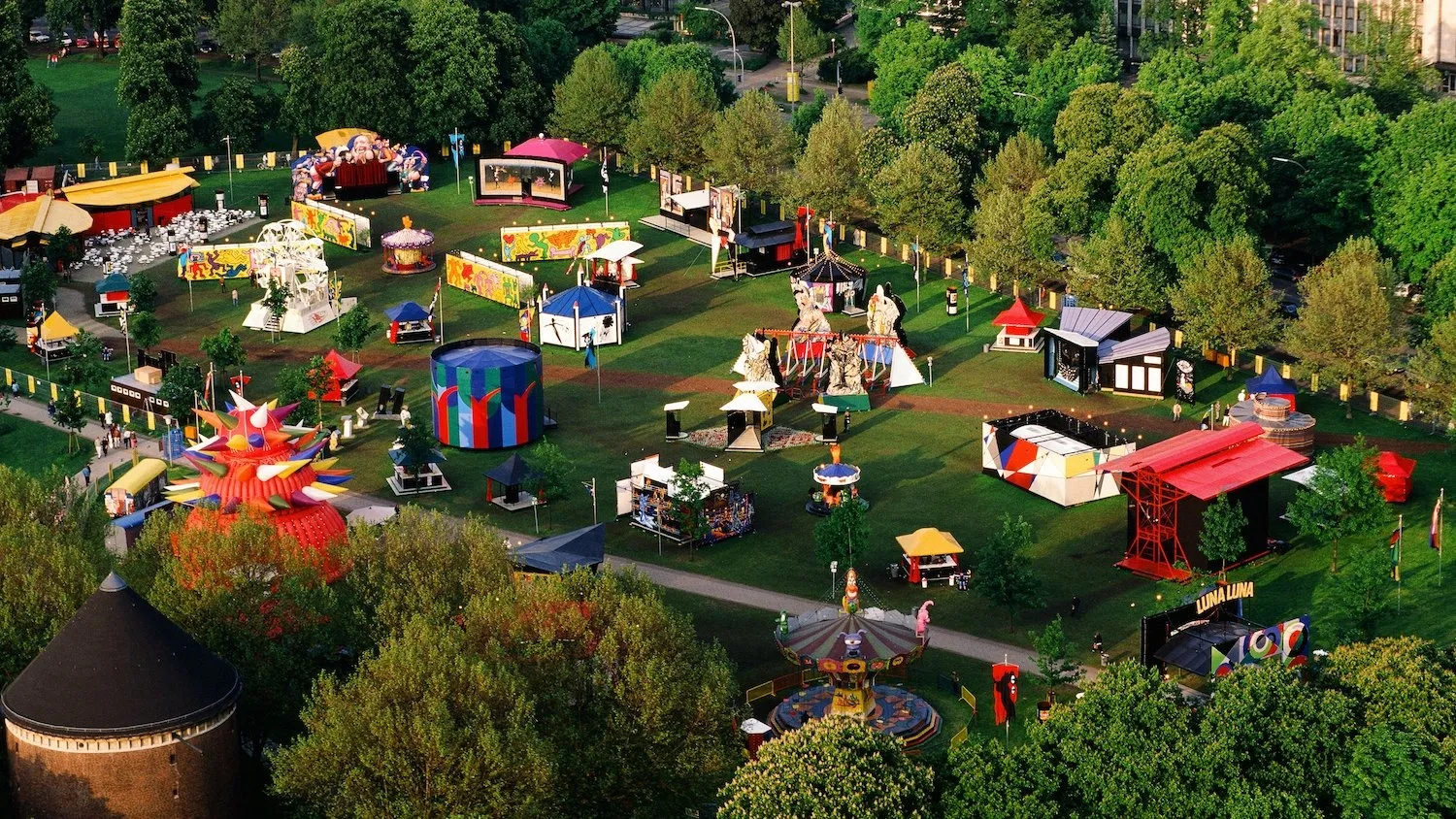 Aerial view of Luna Luna in Moorweide park, Hamburg, Germany, 1987, andre heller avant-garde art situated in fair setting and amid trees.