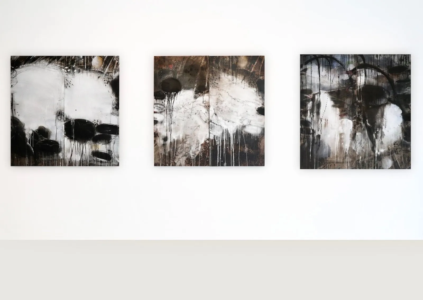 Three abstract ink splash paintings by Kejoo Park hanging on the wall of a gallery exhibition curated by Irene Gong.