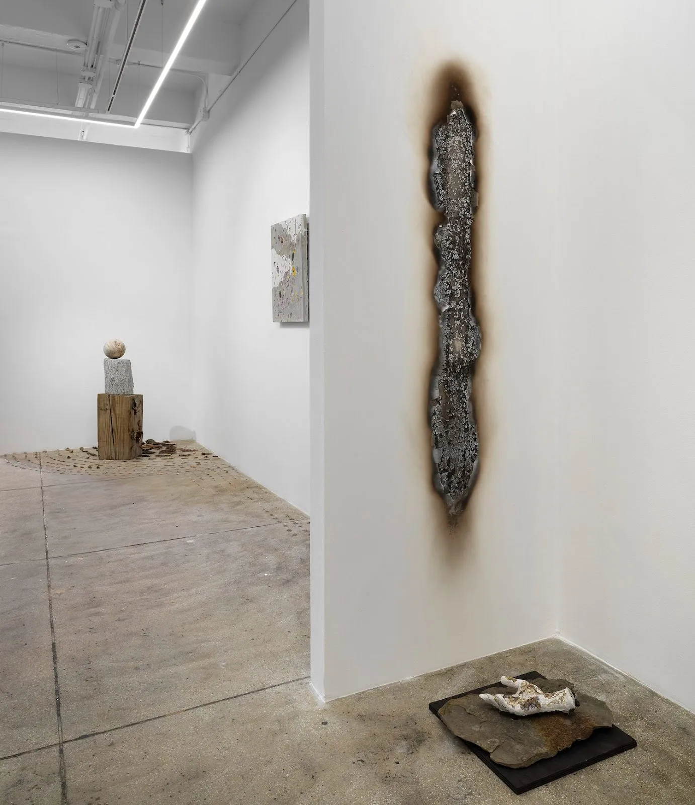 Installation view of Motohiro Takeda: Something To Remember You By at Alison Bradley Projects, burned metal on wall, concrete engraved flower and metal hand sculpture on display.