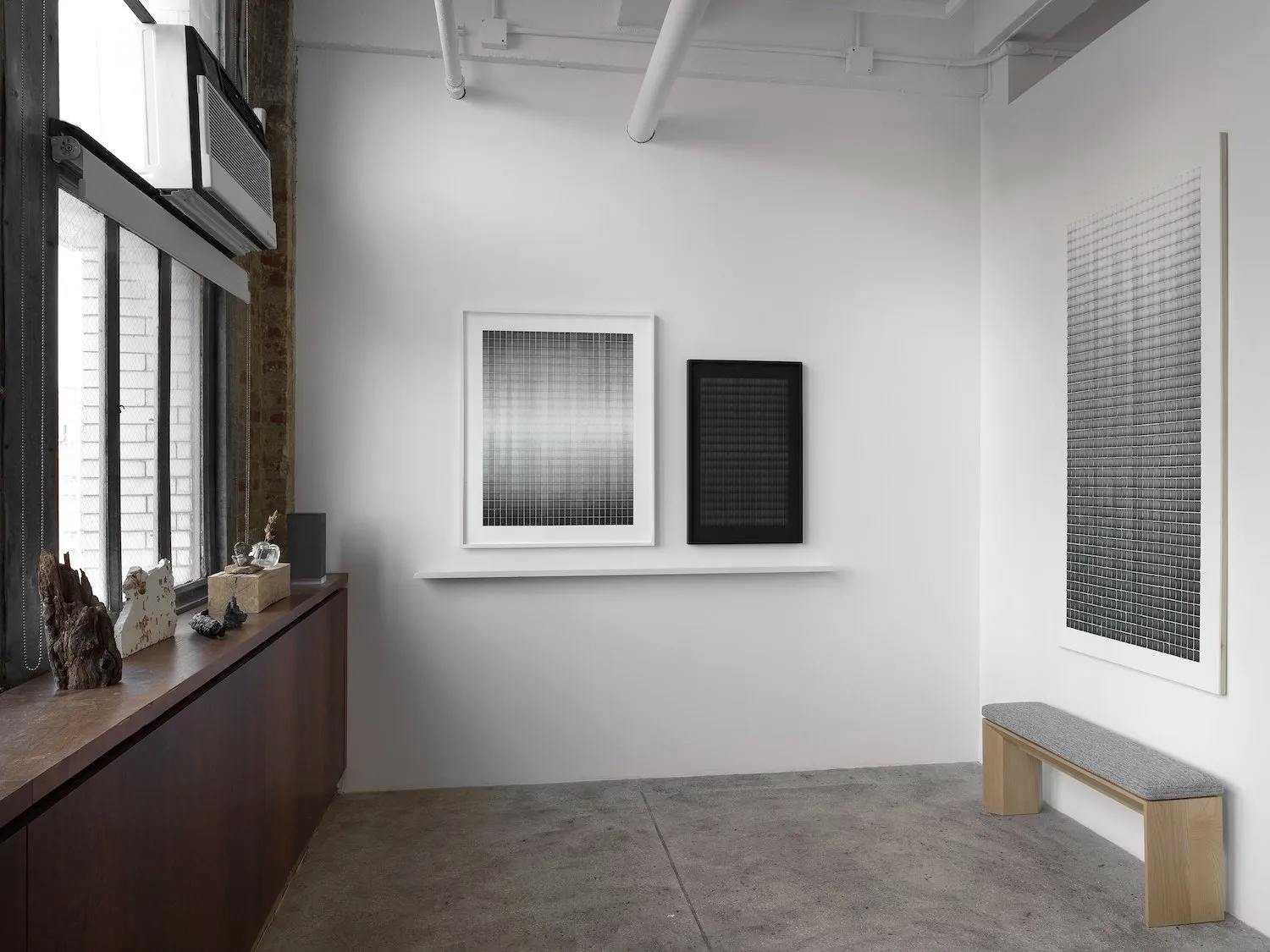 Installation view of Motohiro Takeda: Something To Remember You By at Alison Bradley Projects, black and white abstract paintings with random objects on window sill in office-like setting.