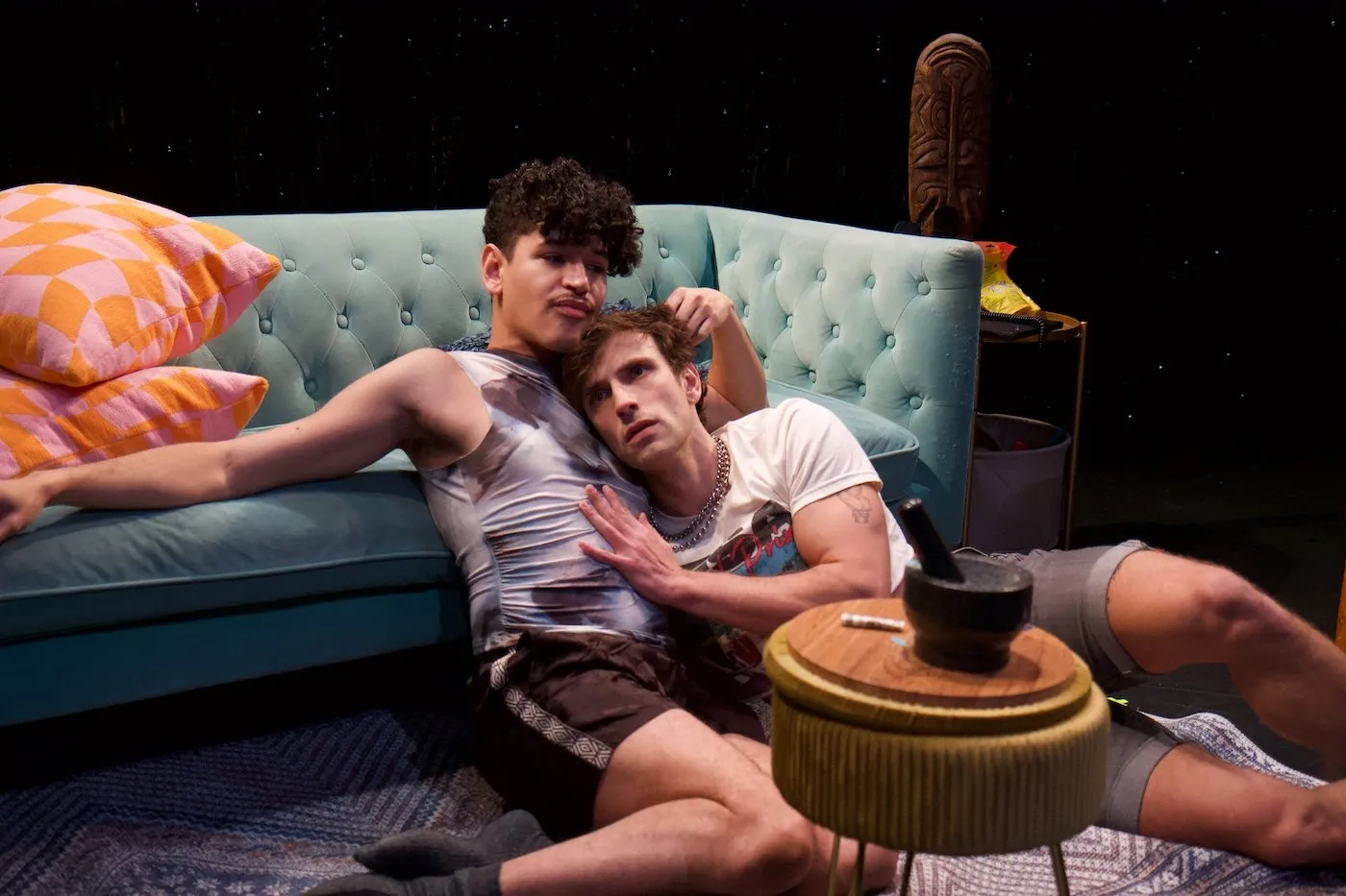 Two men sitting on carpet in front of green couch embracing each other, Sam Gonzalez and Max Kantor in the tank's isle vile.