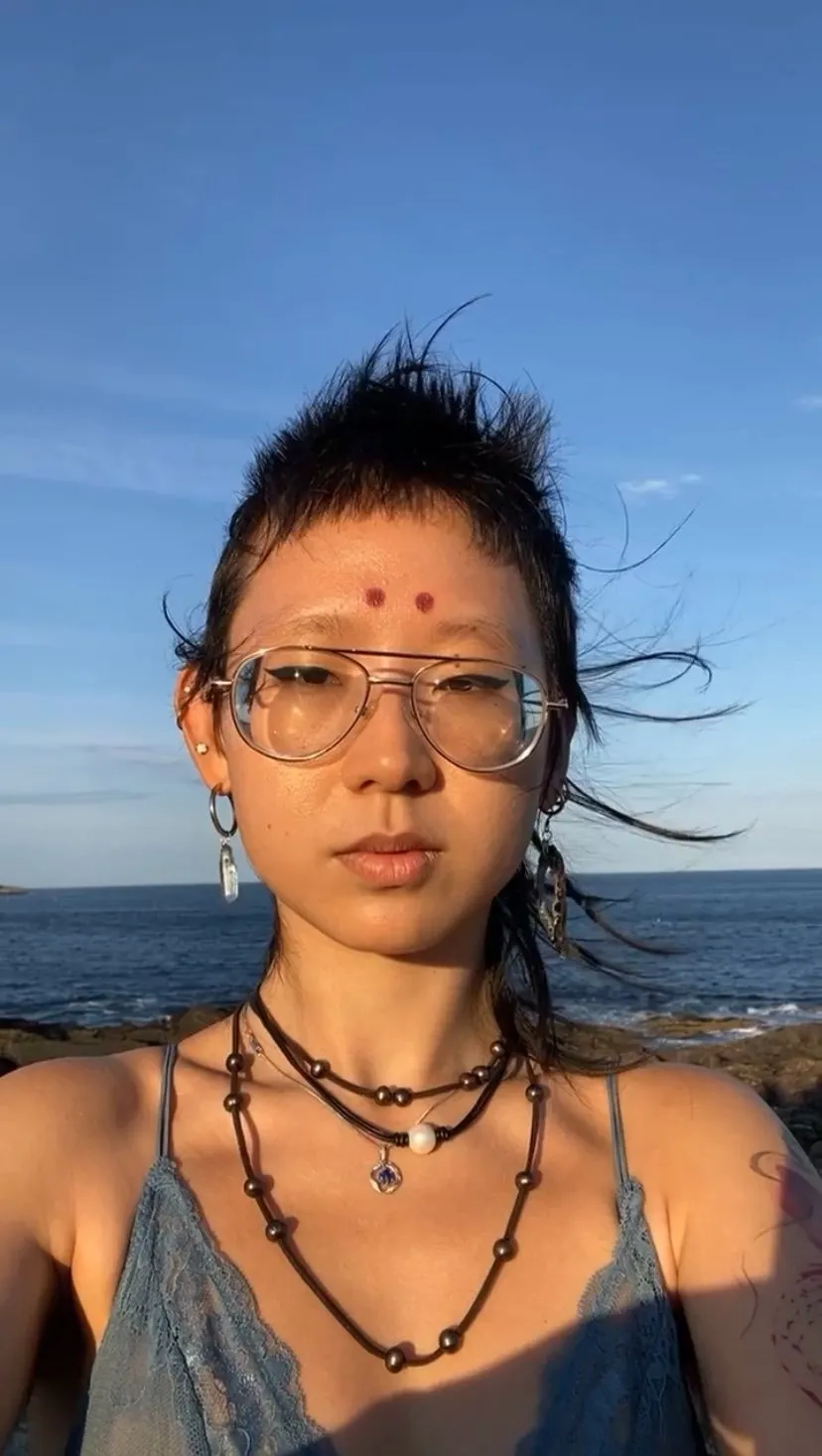 Selfie of Asian photographer with short hair and two red dots on forehead.