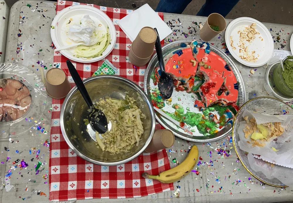 Potluck table with salad, rainbow jello cake, and chips at Artists and Recipes, Marvin Gardens.