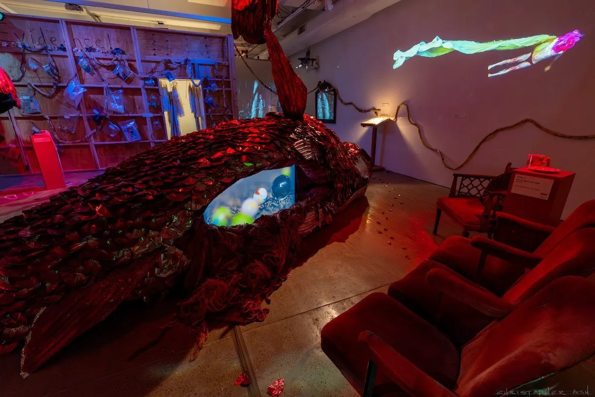 Pink and blue immersive installation gallery, big fish sculpture with rose petals as fish scale, video projection with red couches in the room, the fabric workshop and Museum Philadelphia, gender journey, John Jarboe.