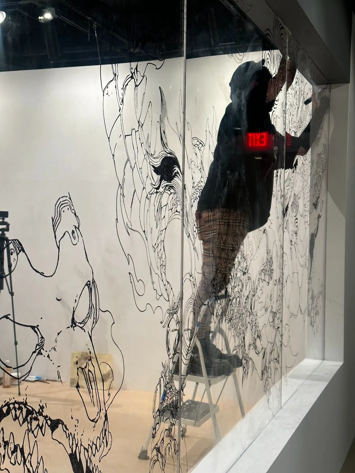 Acky Bright japanese artist solo exhibition studio infinity at japan society, installation view, reviewed by a.e. chapman, the artist drawing performance anime or manga style on glass.