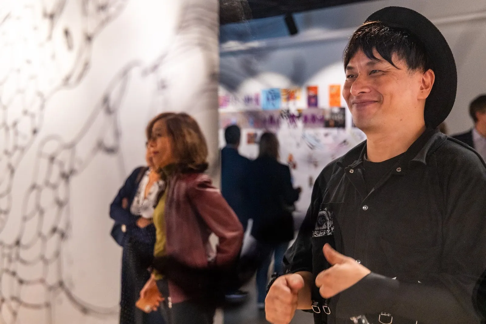 Acky Bright japanese artist solo exhibition studio infinity at japan society, installation view, reviewed by a.e. chapman, the artist smiles at the opening ceremony with viewers.